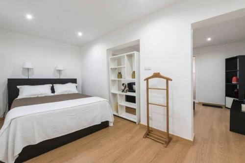 a white bedroom with a bed and a book shelf at Home Lisbon 2 in Lisbon