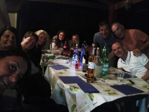 un gruppo di persone seduti intorno a un tavolo con bottiglie di vino di Agriturismo dal Pastore a Follonica