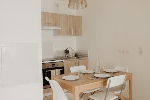 - une cuisine avec une table en bois et des chaises blanches dans l'établissement Bel appartement climatisé avec place de parking, à Marseille