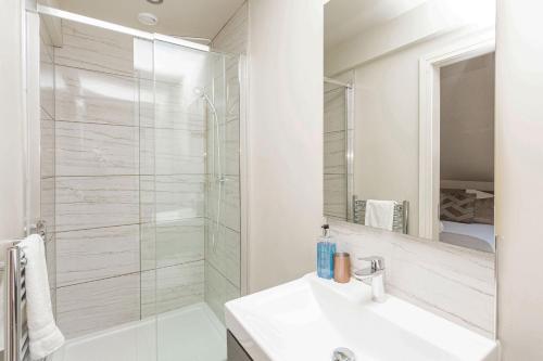 La salle de bains blanche est pourvue d'une douche et d'un lavabo. dans l'établissement Dallicar House, à Settle