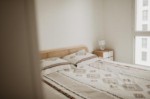 - un lit avec des draps et des oreillers blancs à côté d'une fenêtre dans l'établissement Bel appartement climatisé avec place de parking, à Marseille
