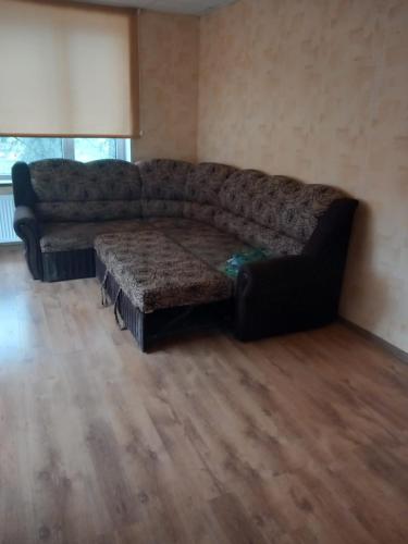 um sofá numa sala de estar com piso em madeira em Balvu centrs Partizanu 10 em Balvi