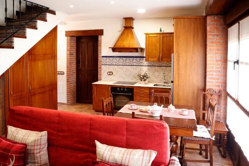 a living room with a red couch in a kitchen at Casa Rural La Tayuela in Luanco