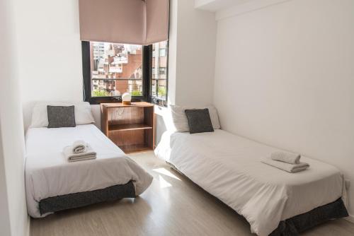 2 camas en una habitación con ventana en Babel Nueva Córdoba en Córdoba