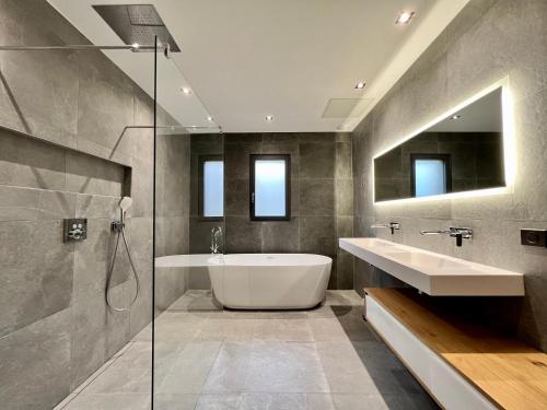 une salle de bain avec une baignoire, un lavabo et une douche dans l'établissement Villa d’exception avec piscine à débordement - vue panoramique, à Saint-Nazaire