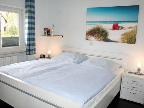a white bed in a bedroom with a picture of the beach at Haus-Am-Sommerdeich-Whg-12 in Sankt Peter-Ording