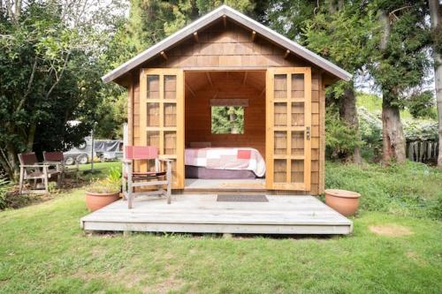 a small wooden house with a bed and a chair at Tui Ridge Eco Cabins in Aongatete