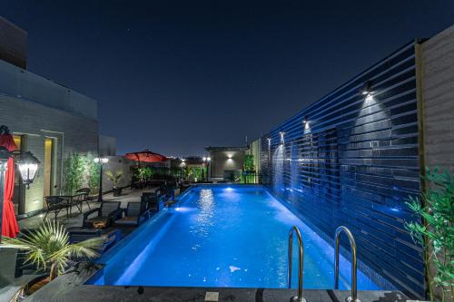 una piscina por la noche con luces en el lateral de un edificio en Land walk Hotel, en Riad