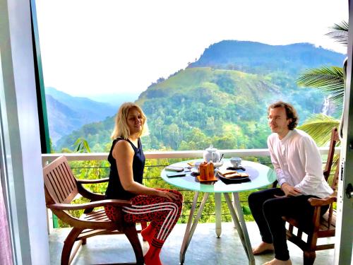a man and a woman sitting at a table on a balcony at Ella HIDE VIEW in Ella