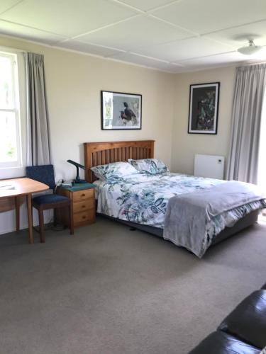 a bedroom with a bed and a desk and a chair at Tui Cottage in Te Arai