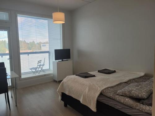 a bedroom with a bed with a television and a balcony at Bright studio apartment on the 6th floor in Kerava
