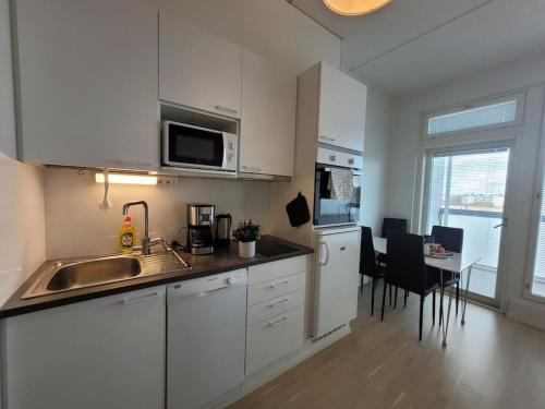 una cocina con armarios blancos y una mesa con sillas. en Bright studio apartment on the 6th floor en Kerava