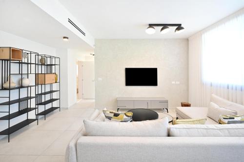 een woonkamer met een bank en een tv bij Summer White by HolyGuest in Tel Aviv