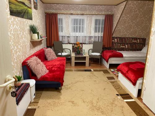 a living room with a red couch and a bed at Haus ZUR PINGE in Kurort Altenberg