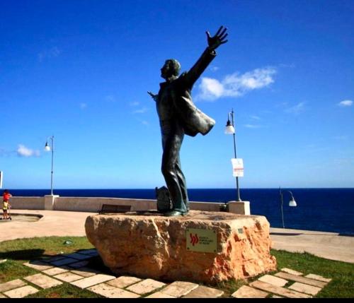 a statue of a woman with her arm in the air at Polignano a Mare: sulla piazza di Domenico Modugno in Polignano a Mare