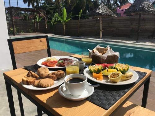 a table with plates of food and a cup of coffee at Lala salama Kendwa villas in Kendwa