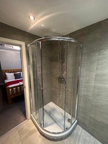 Una ducha de cristal en una habitación con dormitorio en The Hinds Head Hotel en Chorley