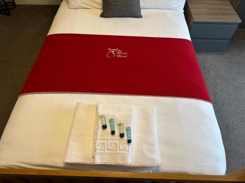 a bed with a red and white comforter with three batteries at The Hinds Head Hotel in Chorley