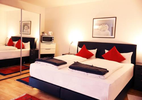 - une chambre avec 2 lits et des oreillers rouges dans l'établissement Hotel Rosenhof GmbH, à Ramstein-Miesenbach