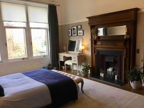 1 dormitorio con 1 cama, chimenea y TV en Spacious 3 bed flat in the heart of the west end. en Glasgow