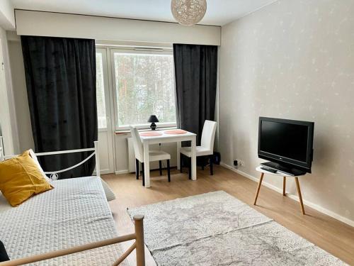 een woonkamer met een televisie en een tafel met stoelen bij Apartment Mariankatu in Kokkola