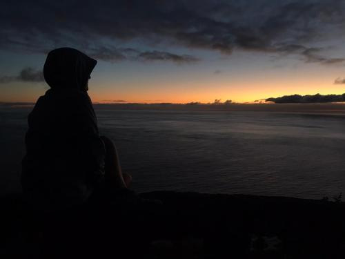 a person sitting in the dark watching the sunset at Modern room (with deck) in Povoação