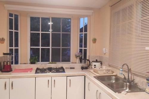 a kitchen with white cabinets and a sink and windows at Casita Independiente, Ubicada Atrás de Nuestra Casa in David