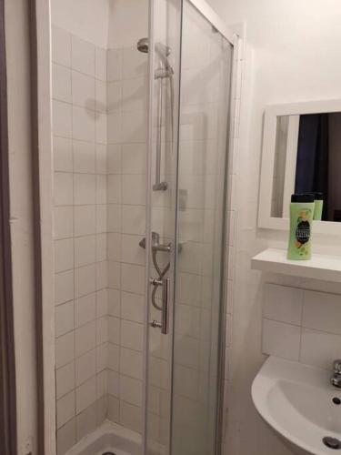 une douche avec une porte vitrée dans une salle de bain dans l'établissement Studio Glacière, à Paris