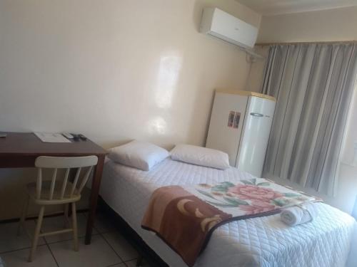 a small bedroom with a desk and a refrigerator at Hotel Do Oeste in Palmitos