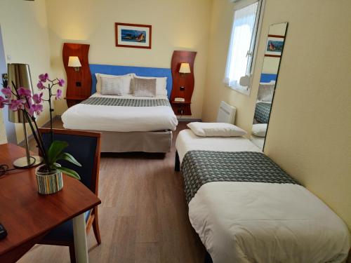 una camera d'albergo con 2 letti e una scrivania di Hôtel Estuaire a Saint-Brévin-les-Pins