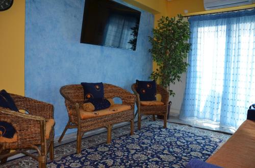 sala de estar con sillas de mimbre y TV en Sunray luxury apartment Volos, en Volos