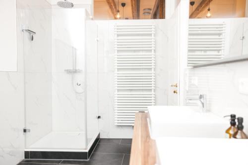 uma casa de banho branca com um chuveiro e um lavatório. em HEIMATEL - Luxury Penthouse Loft em Ravensburg