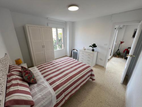 een slaapkamer met een bed met een gestreepte deken bij Zar El Campello in El Campello