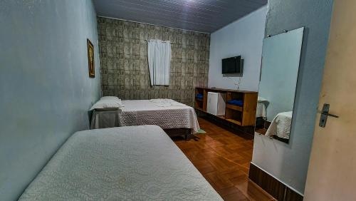 a small room with two beds and a television at Pousada Portal in Chapada dos Guimarães