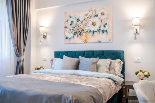 a bedroom with a bed with a painting on the wall at Bliss Land Luxury Apartments in Gura Humorului