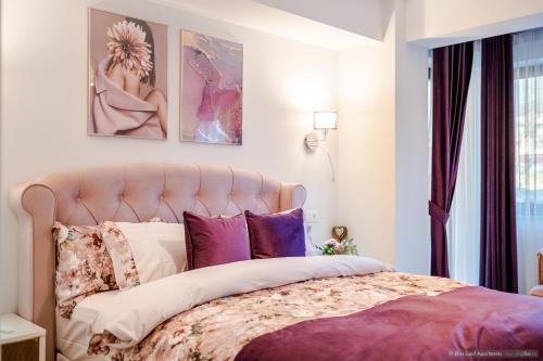 a bedroom with a large bed with purple pillows at Bliss Land Luxury Apartments in Gura Humorului