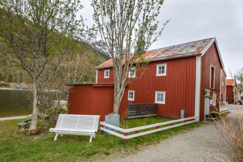 Um celeiro vermelho com um banco à frente. em Sjøgata Riverside Rental and Salmon Fishing em Mosjøen