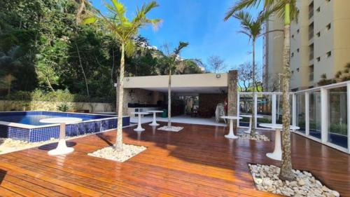 a deck with palm trees and a pool on a building at Recanto das Tartarugas - Guarujá in Guarujá