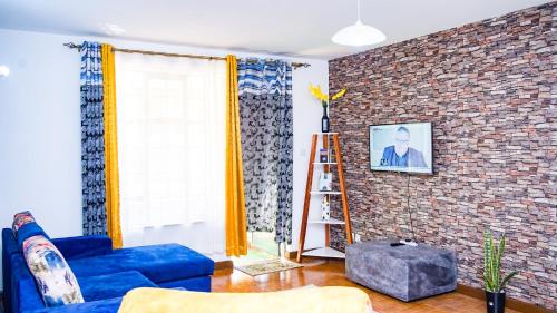 a living room with a blue couch and a brick wall at Primal apartment at Embakasi, Nairobi, Kenya. in Nairobi