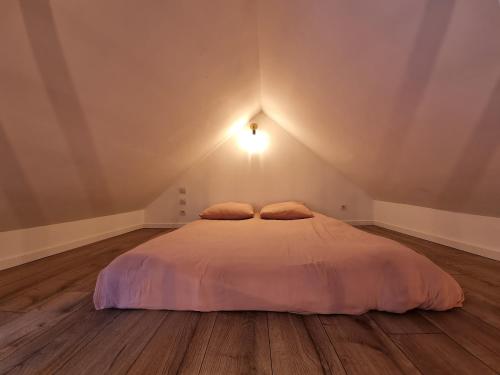 Un dormitorio con una cama blanca con una luz en el techo en La Grange de l'Aber Ildut, en Brélès