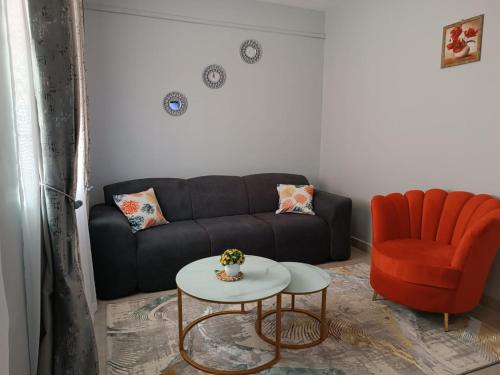 a living room with a black couch and a orange chair at Epic homes, Secure1 bedroom furnished partment, ample Parking and WiFi available in Nyeri