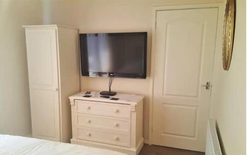1 dormitorio con vestidor y TV de pantalla plana en la pared en Wideopen en Seaton Burn