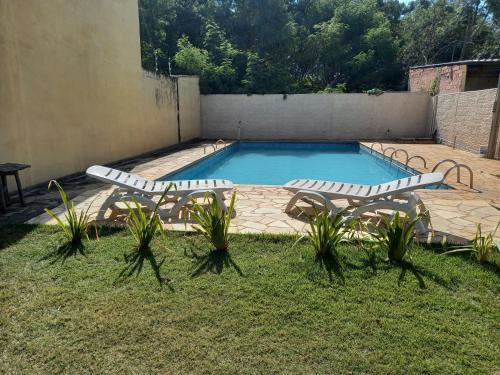 uma piscina com duas espreguiçadeiras e uma mesa em Casa de chácara aconchegante para temporada em São Pedro