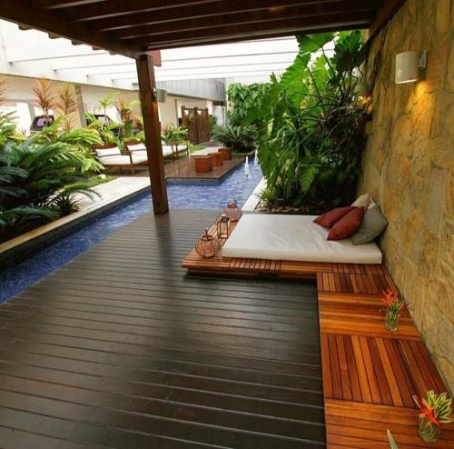 a patio with a bed and some plants at MANDAI Apartamento Cabo Frio in Cabo Frio
