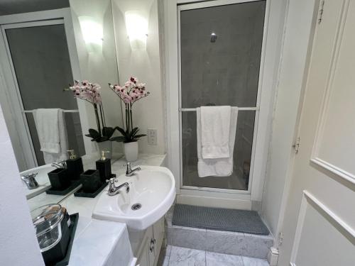 Baño blanco con lavabo y espejo en Double bedroom with en-suite bathroom in Chelsea - central London - share apartment en Londres