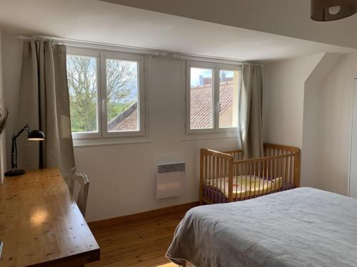a bedroom with a bed and a crib and windows at Maison village, 10 pers, proche de la plage in Audinghen