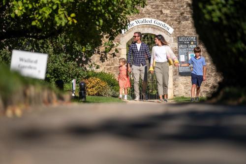 a family standing in front of a stone archway at Woolley Grange - A Luxury Family Hotel in Bradford on Avon