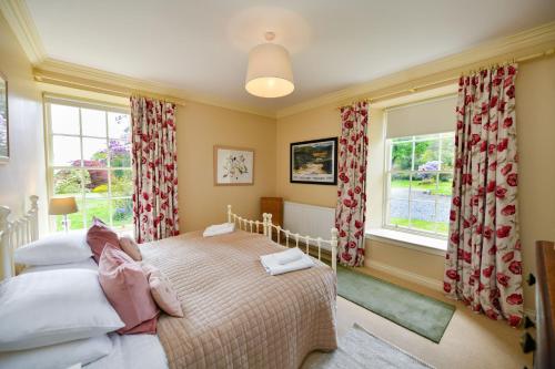 Un dormitorio con dos camas y dos ventanas. en Garden Cottage, en Stranraer