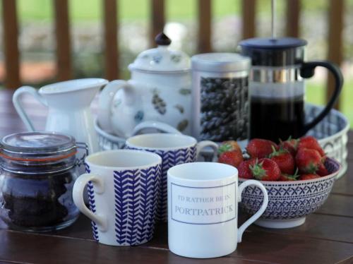 a table topped with cups and a bowl of strawberries at Cedar Lodge in Portpatrick