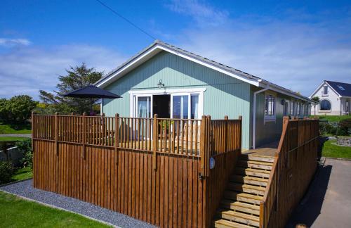 a house with a wooden fence in front of it at Cedar Lodge in Portpatrick
